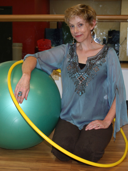 woman kneeling on wood floor with hoop and yoga ball