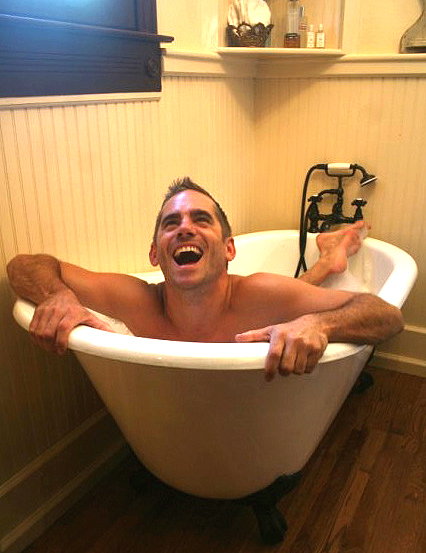 a man emerging from a bathtub laughing